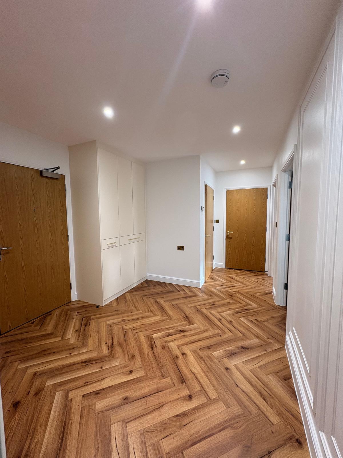 Entrance hallway with herringbone flooring and fitted storage